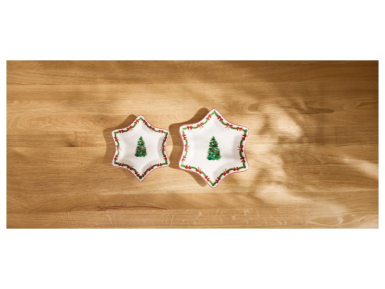 Deux assiettes blanches en forme d'étoile avec des décorations de Noël sur une table en bois.