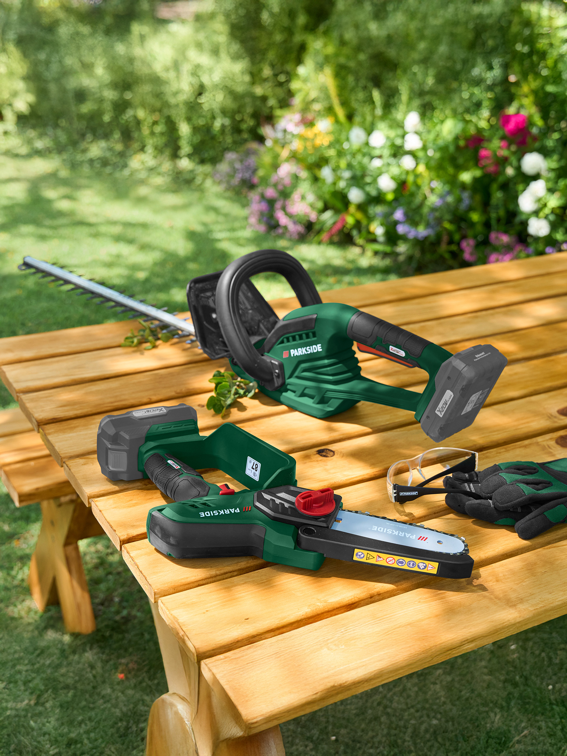 Taille-haie et tronçonneuse sur une table en bois dans le jardin