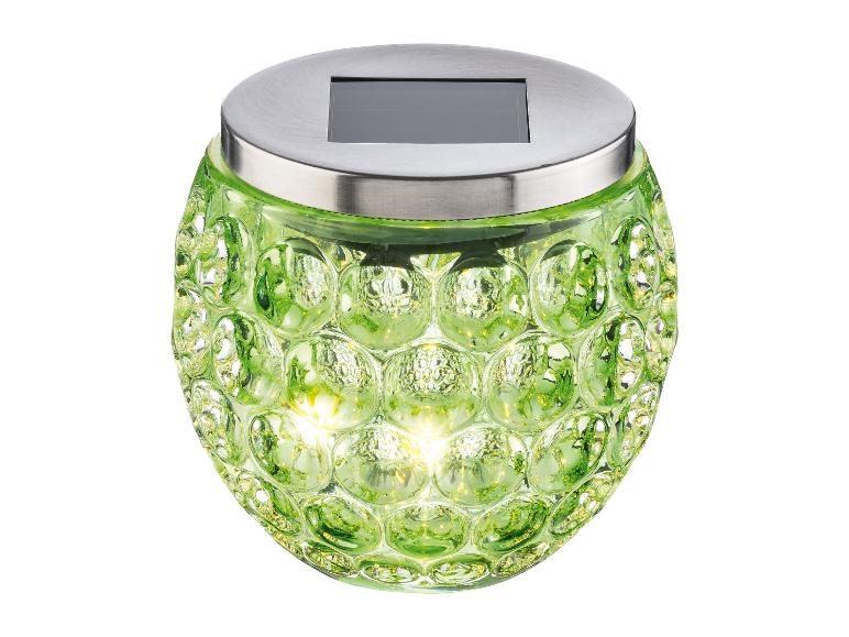 Lampe solaire en verre vert avec surface texturée et couvercle métallique.
