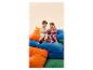 Deux enfants en survêtements et baskets sont assis sur des coussins colorés.