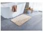Tapis de bain beige devant une baignoire blanche.