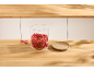 Bocal en verre avec des fraises déshydratées et un couvercle en bois sur un plan de travail.