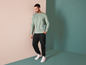 Homme portant un sweat-shirt vert, un pantalon de survêtement noir et des baskets blanches.