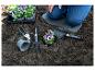 Personne plantant des pensées dans la terre, avec des outils de jardinage et un plateau de semis.