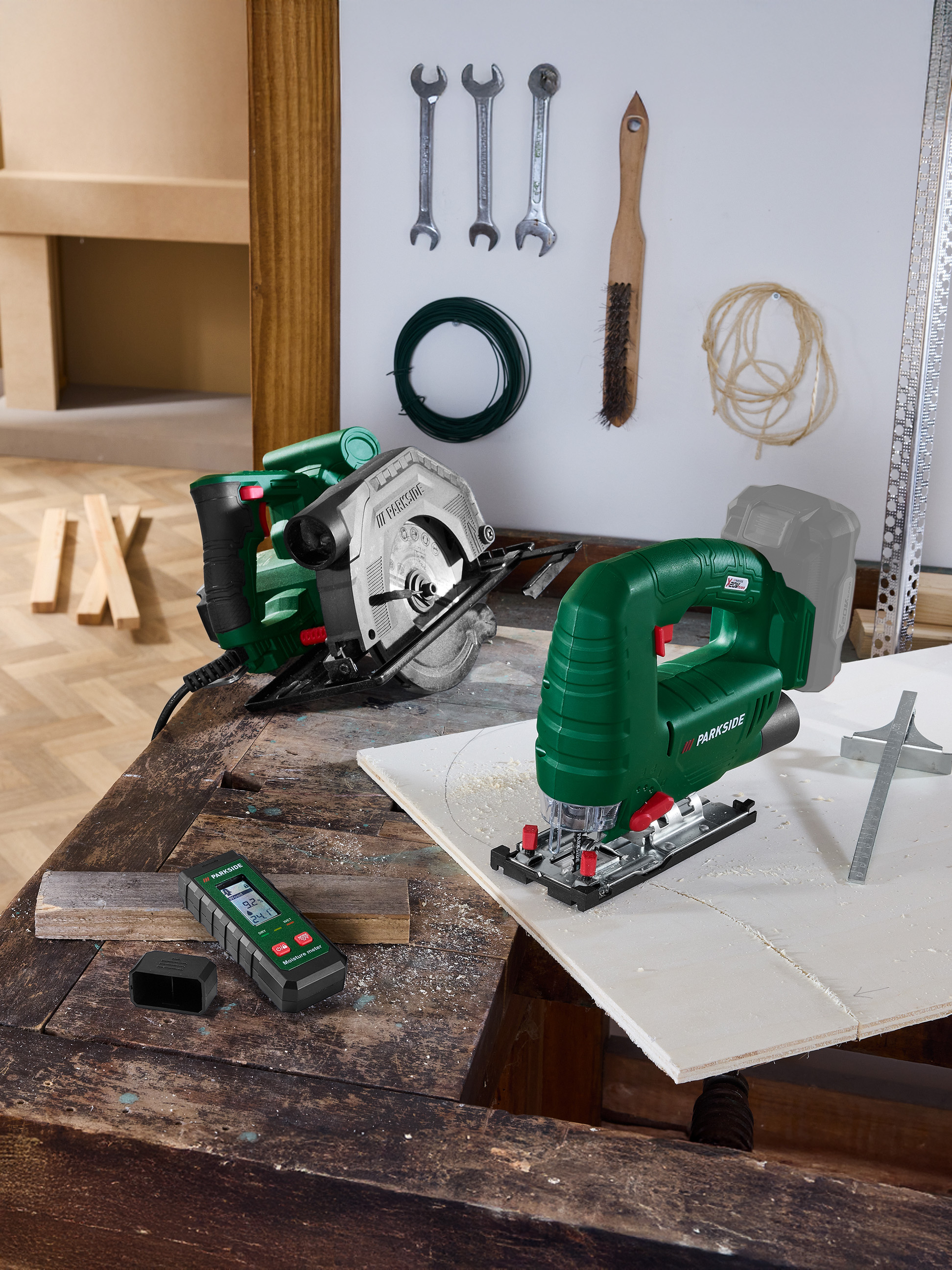 Outils sur un établi: scie circulaire, scie sauteuse et humidimètre.
