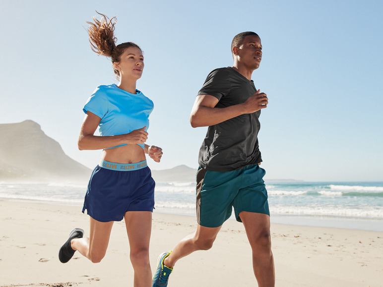Deux personnes courent en tenue de sport sur une plage.