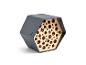 Hôtel à insectes hexagonal avec une coque extérieure gris foncé et un intérieur en bois avec des trous de différentes tailles.