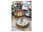 Table dressée avec des plats, dont une salade, et des couverts.
