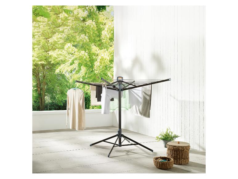 Séchoir à linge avec du linge sur un balcon avec des arbres verts en arrière-plan.