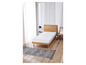 Un matelas blanc sur un sommier en bois avec un tapis gris.