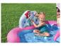 Fille souriante jouant dans une piscine gonflable à l'effigie des princesses Disney sur l'herbe.