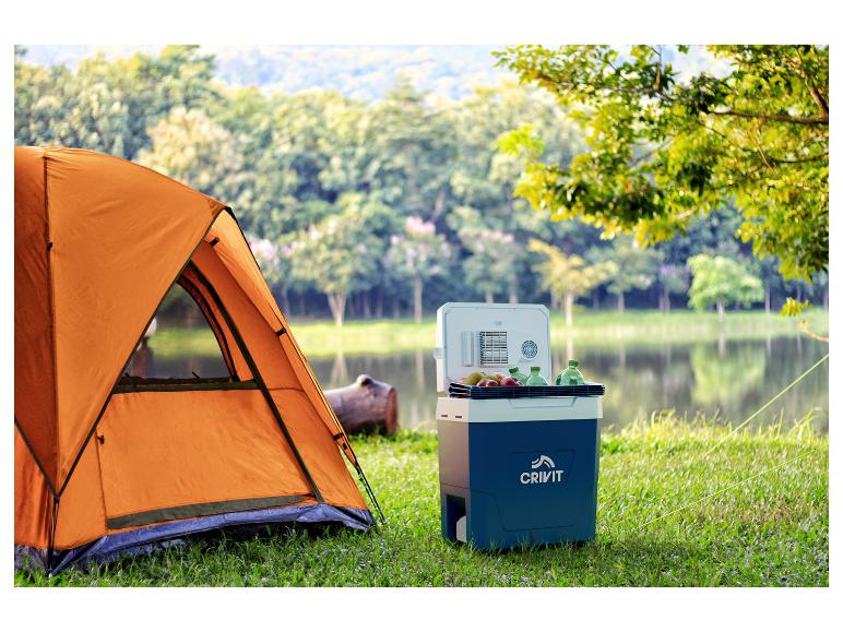 Tente orange et glacière portable bleue avec fruits et boissons au bord du lac.