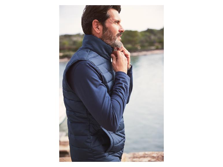 Un homme portant un gilet et un t-shirt à manches longues bleu foncé.