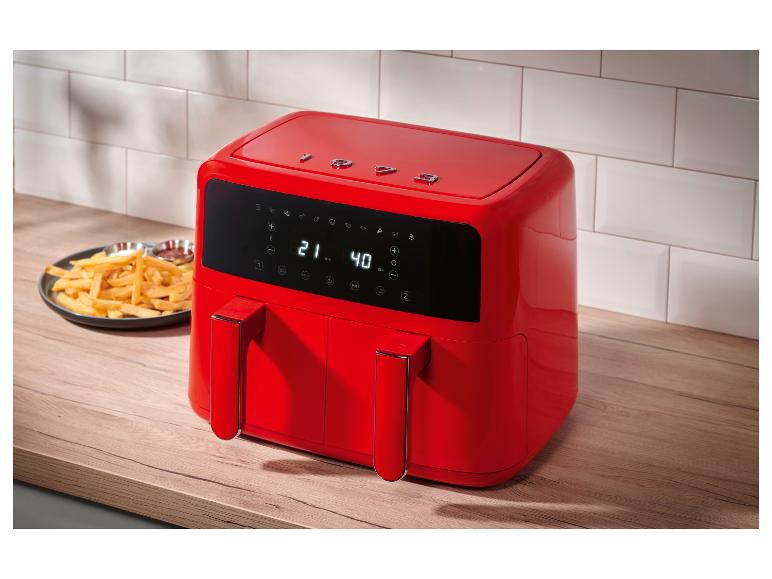 Friteuse à air rouge à double panier sur un comptoir de cuisine en bois avec des frites.