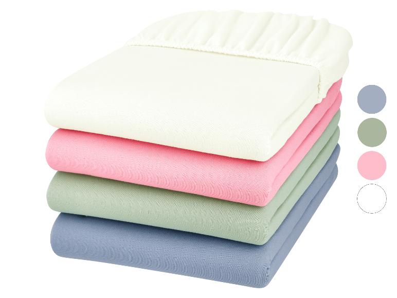 Pile de draps-housses aux couleurs pastel : beige, rose, vert et bleu.