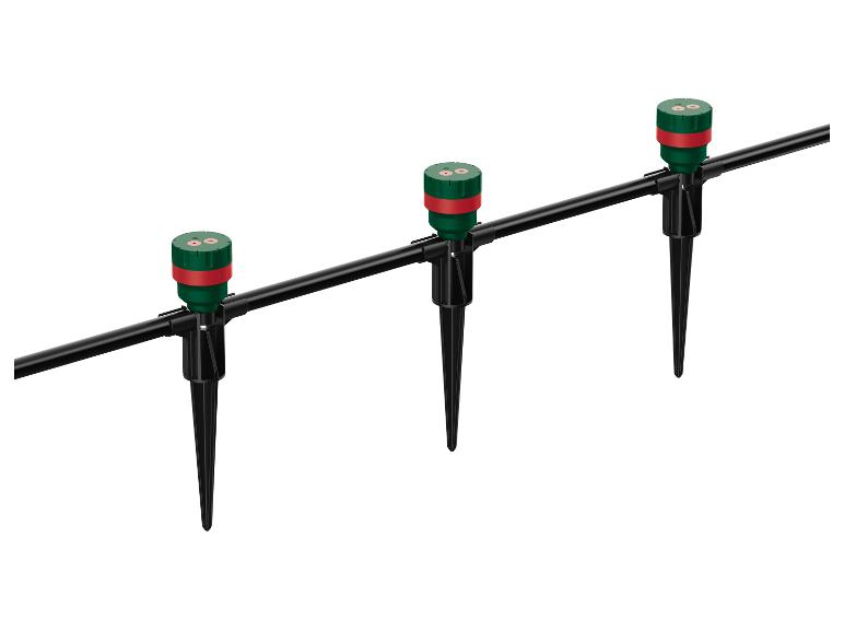 Trois arroseurs de jardin verts et rouges sur des piquets noirs reliés par un tuyau noir.