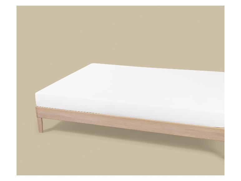 Lit en bois avec matelas blanc sur fond beige clair