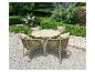 Ensemble de jardin avec table ronde et quatre chaises coussinées sur un chemin de gravier.