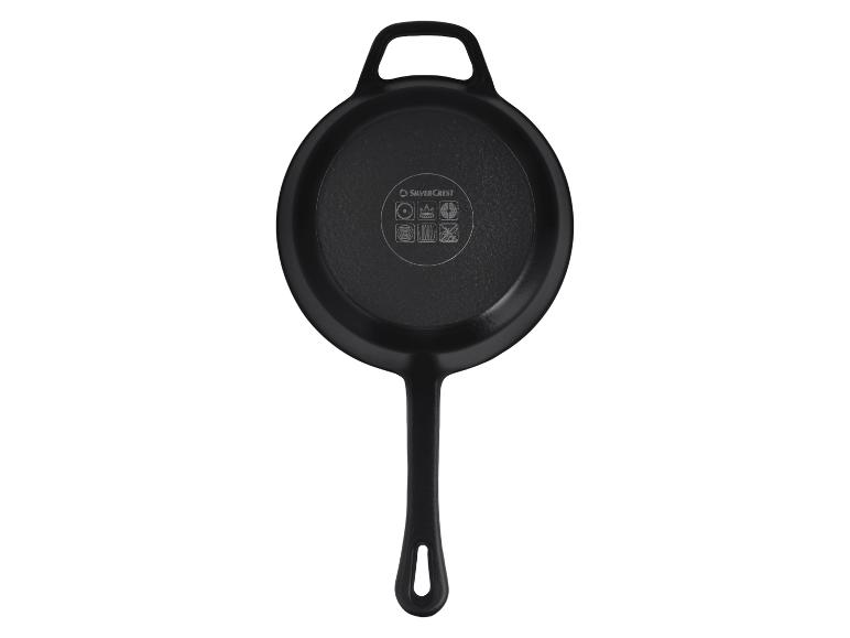 Poêle à frire noire en fonte avec poignée et trou de suspension, dessous avec icônes de cuisson.