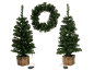 Deux sapins de Noël artificiels en pot et une couronne de Noël, tous illuminés.