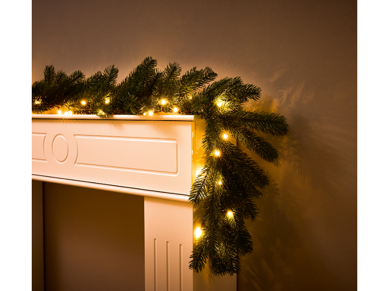 Guirlande de Noël lumineuse sur un manteau de cheminée blanc.