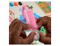 Mains d'enfant tenant une seringue de pâte à modeler rose, avec de la pâte colorée en arrière-plan.
