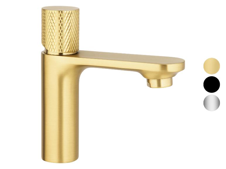 Un robinet moderne à poignée unique, finition or, avec un dessus moleté.