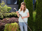 Une femme tient un sécateur dans son jardin.