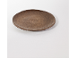 Une assiette unique en céramique marron rustique de forme organique sur une nappe blanche.