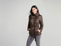 Une femme porte une veste matelassée marron avec une ceinture.