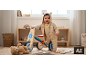 Bébé heureux en tenue tricotée debout à côté d'un vélo d'équilibre en bois à l'intérieur.
