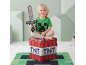 Enfant souriant avec épée jouet, assis sur une boîte de rangement en forme de bloc TNT, sur un tapis à thème jeu vidéo.