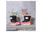 Bottes de pluie enfant noires et roses avec détails jaunes, avec des étoiles scintillantes en arrière-plan.