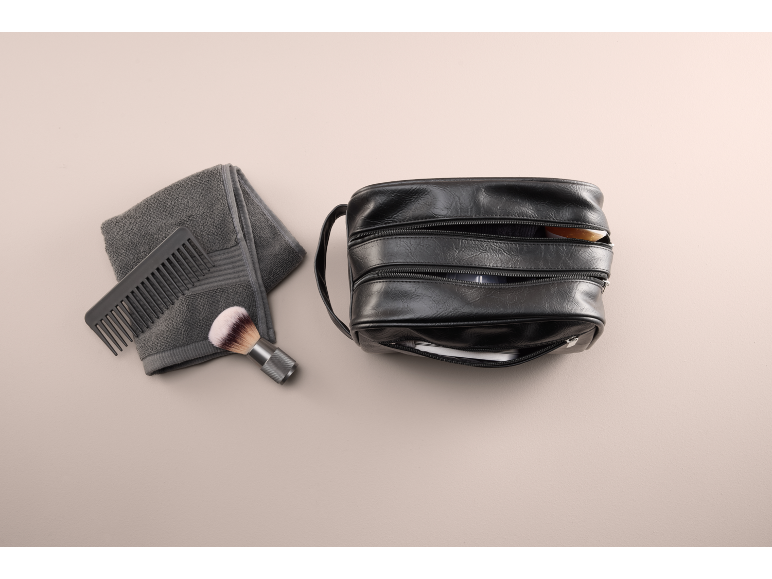 Trousse de toilette noire avec peigne, brosse et serviette grise.