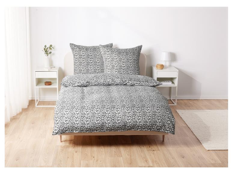 Un lit blanc avec un motif floral noir, y compris des oreillers.