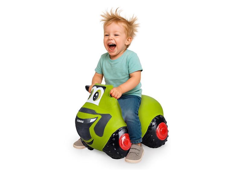 Un jeune enfant s'amuse sur un tracteur Claas gonflable.