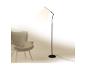 Lampadaire noir moderne éclairant un fauteuil gris dans un intérieur minimaliste.
