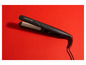 Un fer à lisser Remington noir sur un fond rouge.