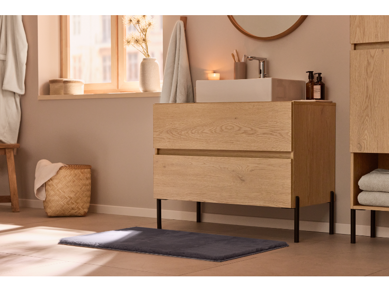 Meuble sous-vasque moderne en bois clair dans une salle de bain chaleureuse.
