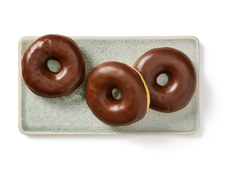 Trois beignets glacés au chocolat sur une assiette rectangulaire texturée bleu clair.