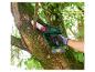 Un homme utilise une tronçonneuse à batterie Parkside pour tailler une branche d'arbre.