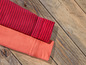 Deux tissus rayés en rouge et orange sur un fond en bois.