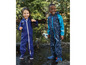 Deux enfants portant des combinaisons de pluie à motifs de bateaux, jouent dans une flaque d'eau.