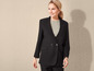 Une femme porte un blazer noir avec un t-shirt gris dessous.
