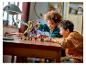 Deux enfants jouent avec un dragon LEGO Ninjago doré et violet et des figurines sur une table en bois.