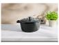 Cocotte en fonte noire sur un comptoir en marbre avec un pot de persil.
