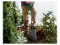 Personne plantant avec une bêche de jardin dans un jardin avec des roses et des buissons.
