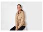 Une femme porte une veste K-Way beige à capuche.