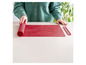Un tapis de cuisson en silicone rouge Coox, roulé sur une table