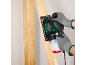 Homme ganté utilisant une ponceuse électrique sur une planche de bois.